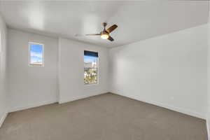 Empty room featuring visible vents, ceiling fan, carpet floors, and baseboards