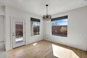 Unfurnished dining area with a notable chandelier, baseboards, and wood finished floors