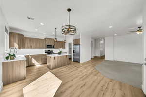 Kitchen with stainless steel appliances, open floor plan, visible vents, and a kitchen island