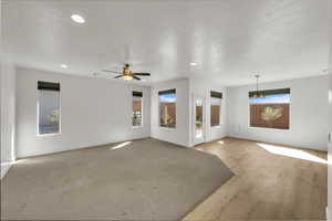Unfurnished living room featuring baseboards, a ceiling fan, plenty of natural light, and recessed lighting