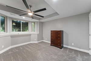 Unfurnished bedroom with carpet, baseboards, a tray ceiling, and visible vents