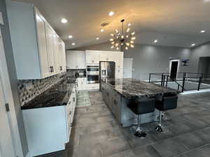 Kitchen with vaulted ceiling, a breakfast bar, stainless steel appliances, and a kitchen island