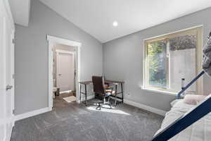 Carpeted office featuring baseboards, lofted ceiling, and visible vents