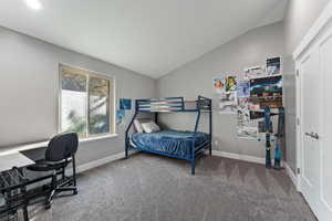 Carpeted bedroom featuring baseboards and vaulted ceiling