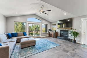 Living room featuring baseboards, lofted ceiling, a tiled fireplace, and a ceiling fan