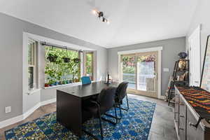 Office space with baseboards, visible vents, and vaulted ceiling