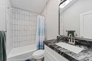 Full bath with shower / tub combo with curtain, toilet, and vanity
