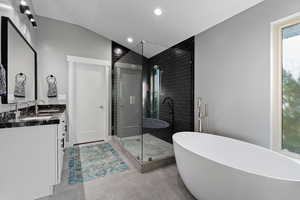Full bath featuring vanity, vaulted ceiling, recessed lighting, a stall shower, and a freestanding bath