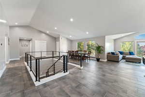 Hallway with baseboards, lofted ceiling, an upstairs landing, and recessed lighting