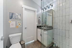 Full bathroom with tile patterned floors, toilet, tiled shower, and vanity