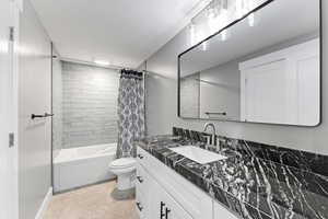 Bathroom with tile patterned floors, toilet, vanity, and shower / bath combo with shower curtain