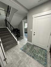 Foyer featuring lofted ceiling, baseboards, stairs, and visible vents