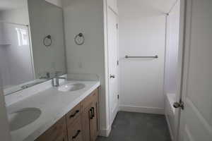 Full bath featuring double vanity, baseboards, and a sink