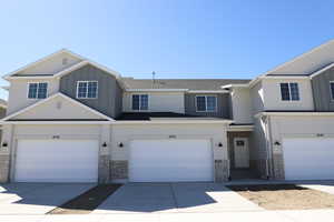 Multi unit property featuring stone siding, driveway, a shingled roof, and board and batten siding
