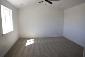 Spare room with light colored carpet, lofted ceiling, baseboards, and a ceiling fan