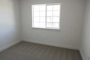 Spare room featuring baseboards and dark colored carpet