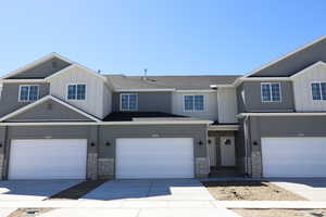 View of front of house with stone siding, a garage, concrete driveway, board and batten siding, and roof with shingles