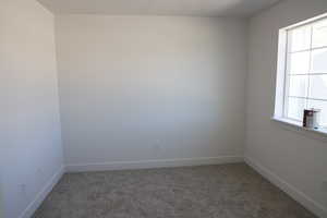 Spare room featuring baseboards and carpet flooring