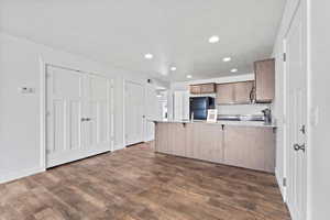 Kitchen with recessed lighting, dark wood-type flooring, a peninsula, and freestanding refrigerator