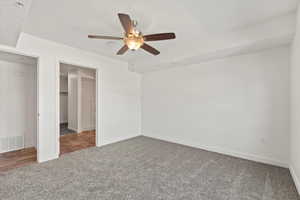 Unfurnished bedroom with a closet, carpet flooring, a ceiling fan