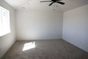 Unfurnished room with lofted ceiling, carpet flooring, baseboards, visible vents, and a ceiling fan