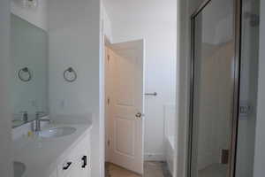 Full bath featuring a bath, double vanity, a sink, and walk in shower
