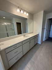 Bathroom with baseboards, a stall shower, tile patterned flooring, and vanity