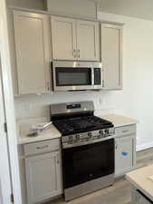 Kitchen with light wood finished floors, baseboards, light countertops, and stainless steel appliances