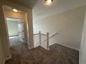 Hallway with baseboards, an upstairs landing, and carpet
