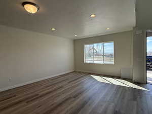 Unfurnished room featuring dark wood-type flooring, baseboards, and recessed lighting