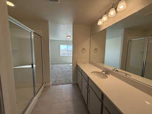 Bathroom featuring a shower stall, tile patterned floors, vanity, and a textured ceiling