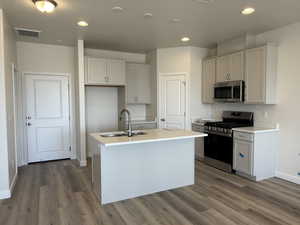 Kitchen featuring a sink, dark wood-style floors, visible vents, a kitchen island with sink, and appliances with stainless steel finishes