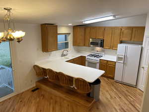 Kitchen/Dining area with vaulted ceilings, solid-surface countertops, hardwood cabinetry and bar.