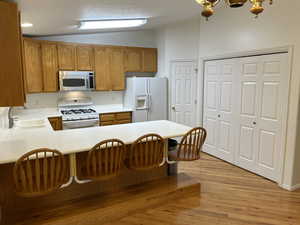 Kitchen/Dining area with vaulted ceilings, solid-surface countertops, hardwood cabinetry and bar.