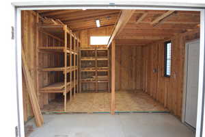 Interior of storage shed with shelving, windows, and vaulted ceiling. Two access doors.