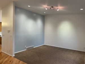 Large entry/living room are with vaulted ceilings. Hardwood and carpeted surfaces.