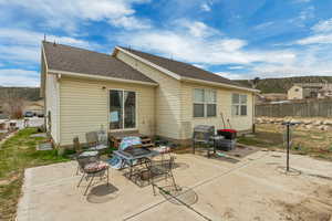 Rear view of house with a patio area, a shingled roof, and fence