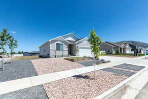View of front of house with a residential view, driveway, stone siding, and an attached garage