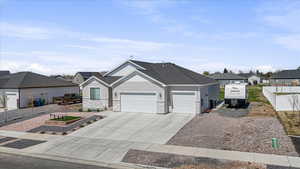 Single story home featuring driveway, stone siding, fence, a garage, and a residential view