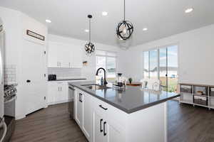 Kitchen featuring dark wood-type flooring, a sink, dark countertops, and appliances with stainless steel finishes