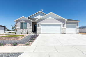 Ranch-style house featuring stone siding, driveway, a garage, and fence