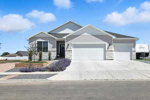 Craftsman-style house featuring a garage, stone siding, and concrete driveway