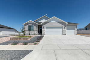 View of front of property featuring stone siding, an attached garage, fence, and concrete driveway