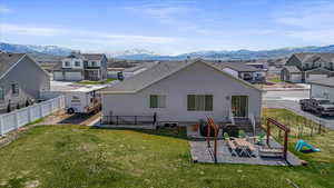 Rear view of house with a yard, a mountain view, fence, and a residential view