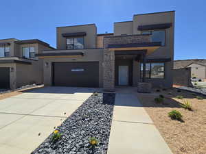 Modern home with stucco siding, an attached garage, and driveway