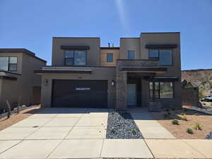 Modern home featuring stucco siding, driveway, a garage, and stone siding