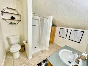 Bathroom featuring a textured ceiling, vanity, a stall shower, and light tile patterned flooring
