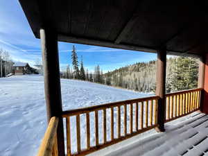 Snow covered deck featuring a forest view