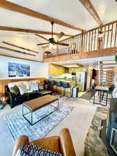 Living room featuring high vaulted ceiling, wood walls, wainscoting, a ceiling fan, and beamed ceiling