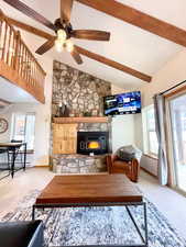 Living area featuring high vaulted ceiling, light colored carpet, a ceiling fan, beam ceiling, and a baseboard radiator